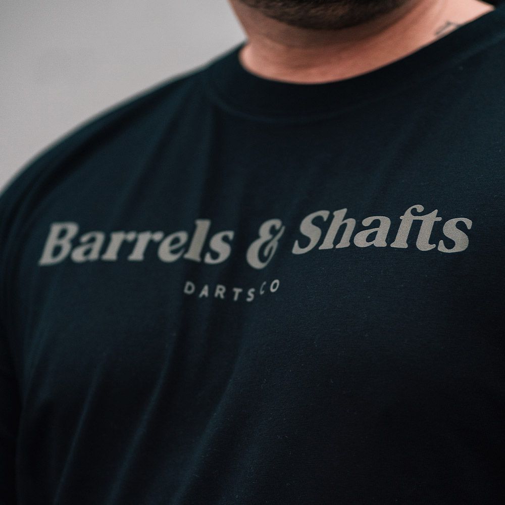 Tričko Barrels and Shafts - Černé Das Bild zeigt ein schwarzes T-Shirt mit der Aufschrift "Barrels & Shafts". Darunter steht in kleineren Buchstaben "DARTSCO".