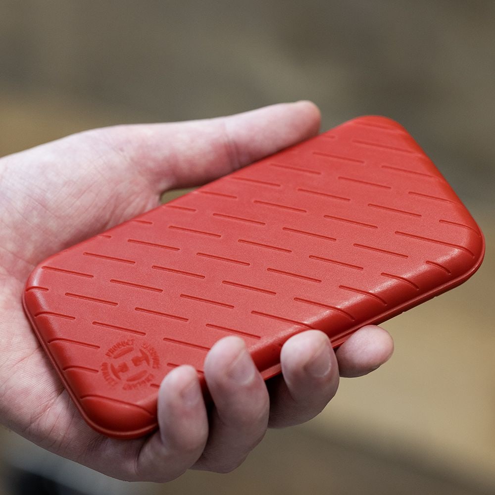 Pouzdro na šipky Harrows Slimcase Eine Person hält eine rote, strukturierte Darttasche in der Hand. Die Darttasche hat eine schlanke und kompakte Form.