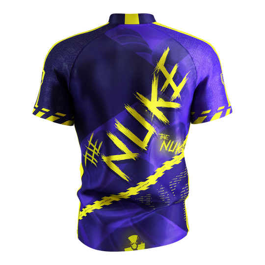 Das Bild zeigt das „Target Coolplay Luke Littler 2025 Dartshirt“ von hinten. Das Shirt ist überwiegend lila mit auffälligen gelben Designs und dem Schriftzug „NUKE“ auf dem Rücken.