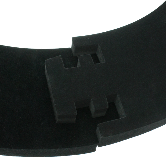 DBS3S_Bulls_Quarterback_Surround_Schwarz_4 Das Bild zeigt ein Produkt namens „Quarterback Surround“. Es handelt sich um ein gebogenes, schwarzes Schaumstoffelement mit geometrischen Aussparungen.