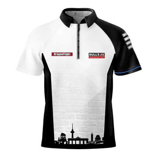 Das Bild zeigt das Bulls Martin Schindler The Wall Dartshirt mit einem schwarz-weißen Design und kurzen Ärmeln. Auf der Vorderseite befinden sich Logos und eine stilisierte Stadtsilhouette am unteren Rand.