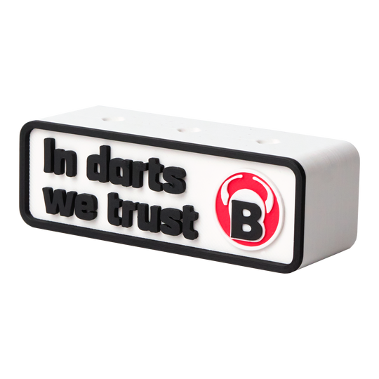 Das Bild zeigt einen weißen Dartshalter mit der Aufschrift "In darts we trust". Daneben befindet sich ein rotes Logo mit dem Buchstaben "B".