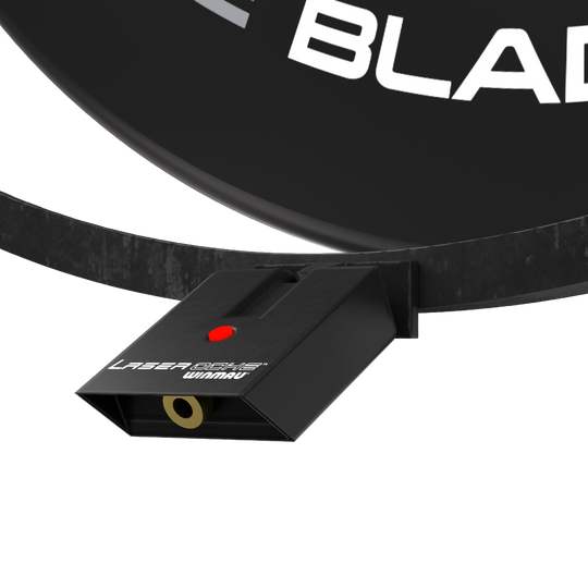 Sada příslušenství Winmau Plasma Das Bild zeigt das Winmau Plasma Zubehör Set, das an einem Dartboard befestigt ist. Sichtbar ist ein schwarzes Gerät mit der Aufschrift "Laser Oche Winmau" und einem roten Knopf.