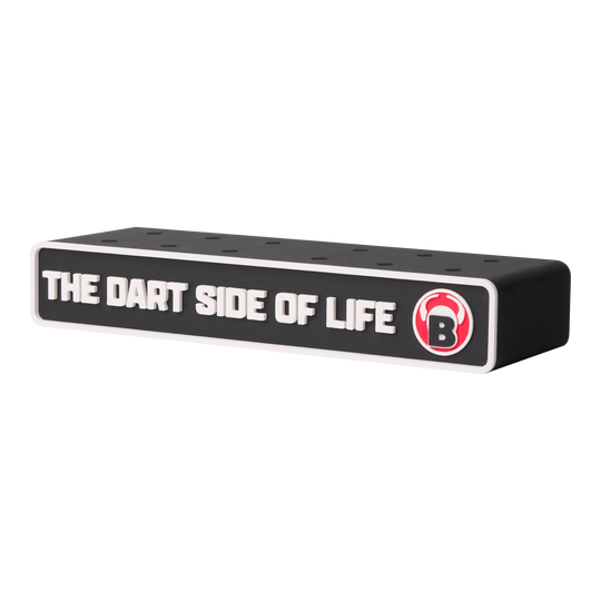 Das Bild zeigt einen schwarzen Dart-Halter mit der Aufschrift "THE DART SIDE OF LIFE". Rechts ist ein rotes Logo mit einem weißen "B" zu sehen.