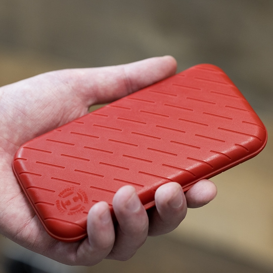 Pouzdro na šipky Harrows Slimcase Eine Person hält eine rote, strukturierte Darttasche in der Hand. Die Darttasche hat eine schlanke und kompakte Form.