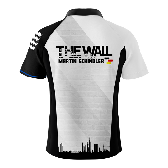 Das Bild zeigt das "Bulls Martin Schindler The Wall Dartshirt" von hinten. Auf dem Shirt steht "THE WALL MARTIN SCHINDLER" mit einer kleinen Deutschlandflagge und einer Stadtsilhouette darunter.