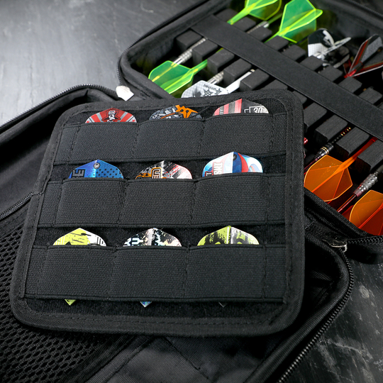 In dem Bild sieht man ein schwarzes Dartetui, das verschiedene Darts und Dart-Flights ordentlich aufbewahrt. Die Darts sind auf der rechten Seite einsortiert, während links viele bunte Flights in Fächern stecken.
