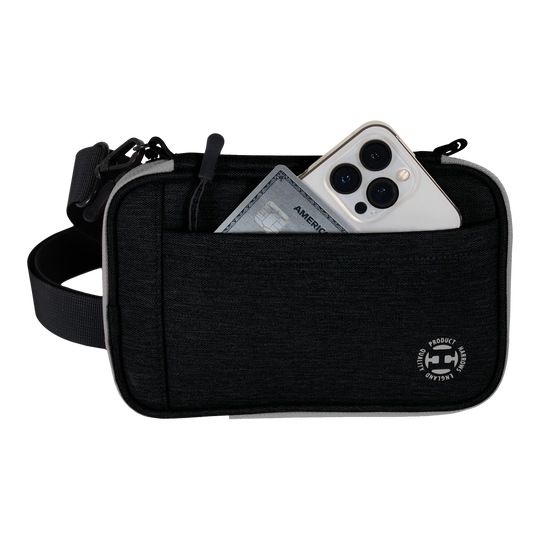 Peněženka na šipky Harrows Smart Case XL Auf dem Bild ist eine schwarze Harrows Smart Case XL Darttasche zu sehen. In der vorderen Tasche stecken ein Smartphone und eine Kreditkarte.